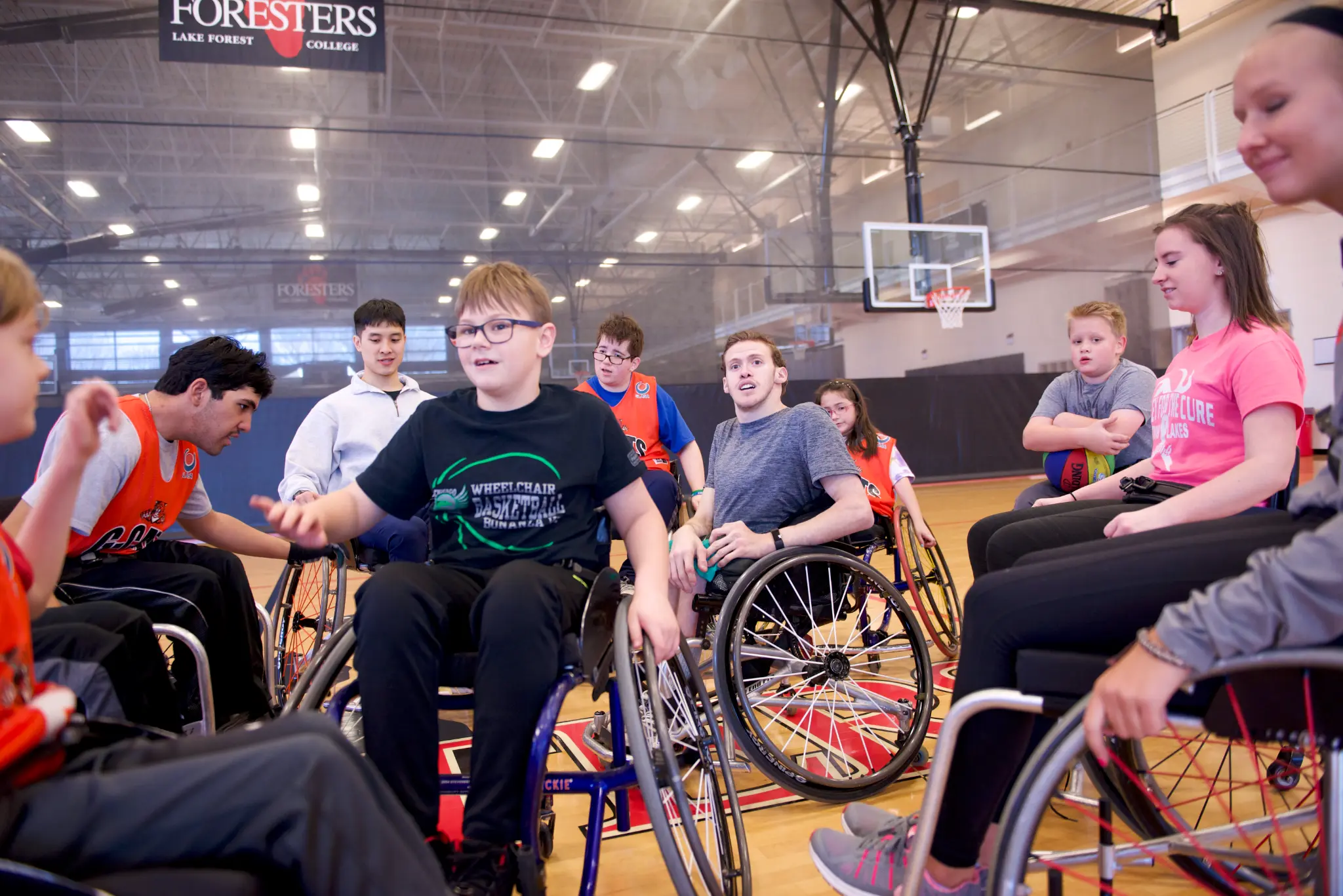 Alec Tranel coaching young wheelchair basketball athletes in a gymnasium